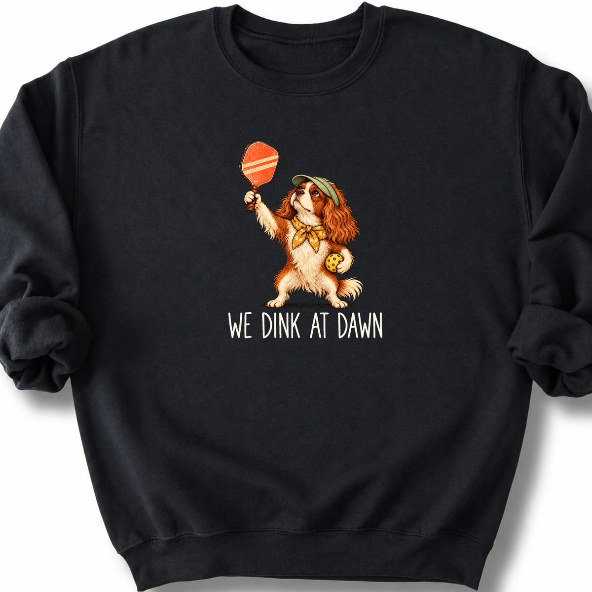 Cavalier with a pickleball paddle and ball on a Black Gildan® sweatshirt with We Dink at Dawn text