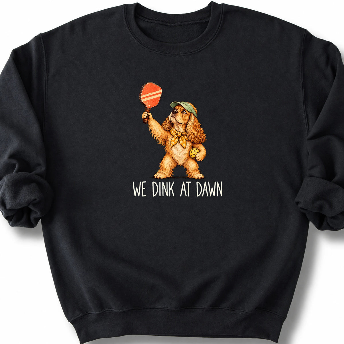 Cocker Spaniel with a pickleball paddle and ball on a Black Gildan® sweatshirt with We Dink at Dawn text