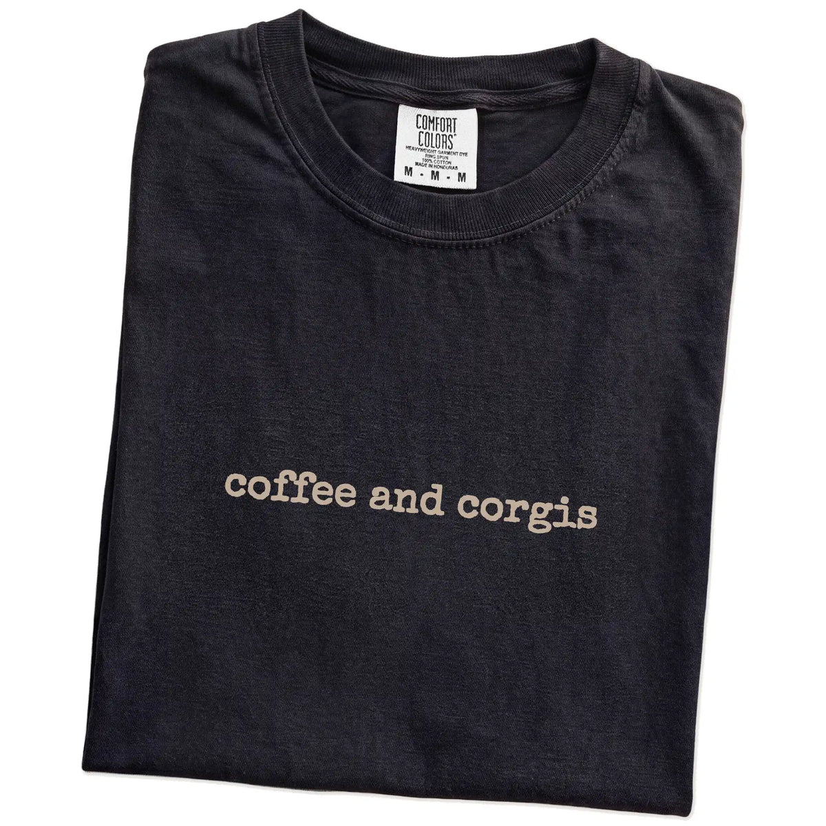 Folded Black Comfort Colors® T-shirt showing “coffee and corgis” retro text