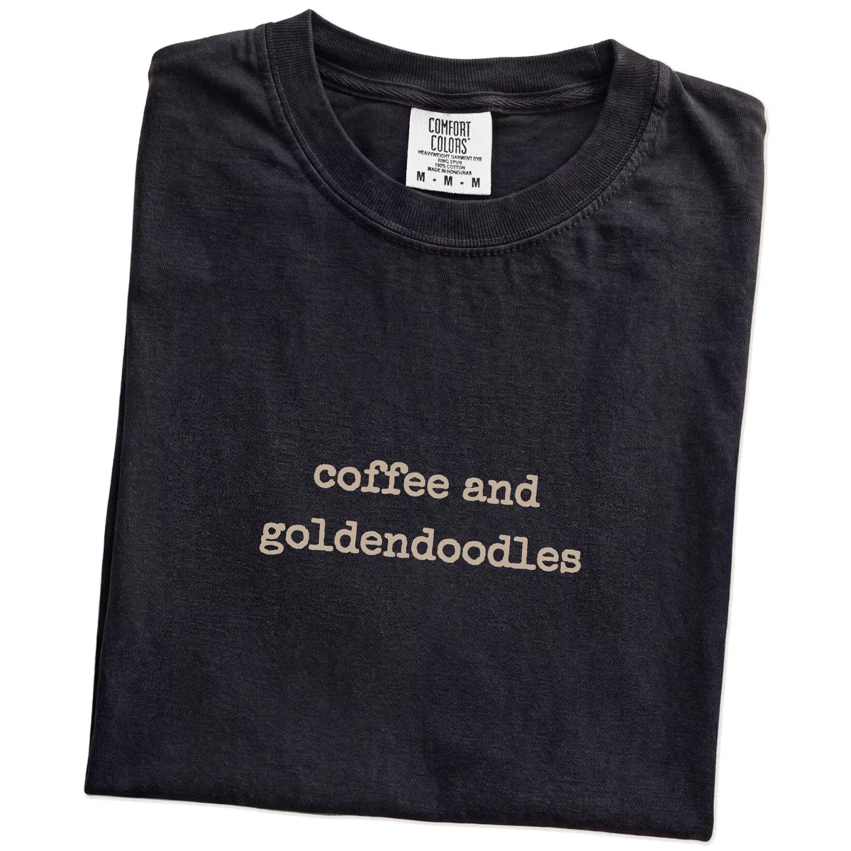 Folded Black Comfort Colors® T-shirt showing “coffee and goldendoodles” retro text