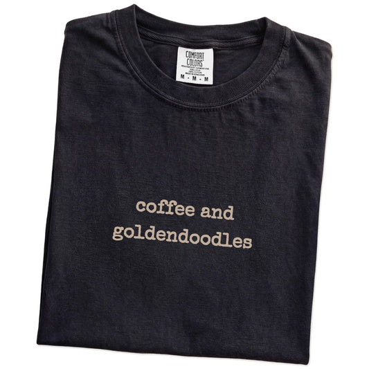 Folded Black Comfort Colors® T-shirt showing “coffee and goldendoodles” retro text