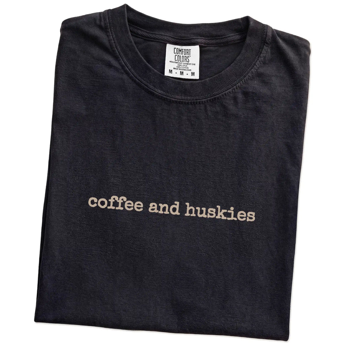 Folded Black Comfort Colors® T-shirt showing “coffee and huskies” retro text