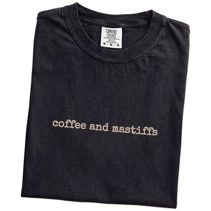 Folded Black Comfort Colors® T-shirt showing “coffee and mastiffs” retro text