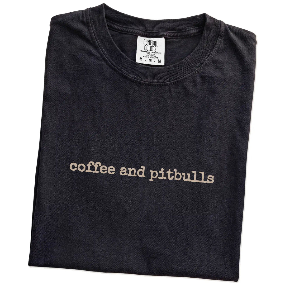 Folded Black Comfort Colors® T-shirt showing “coffee and pitbulls” retro text