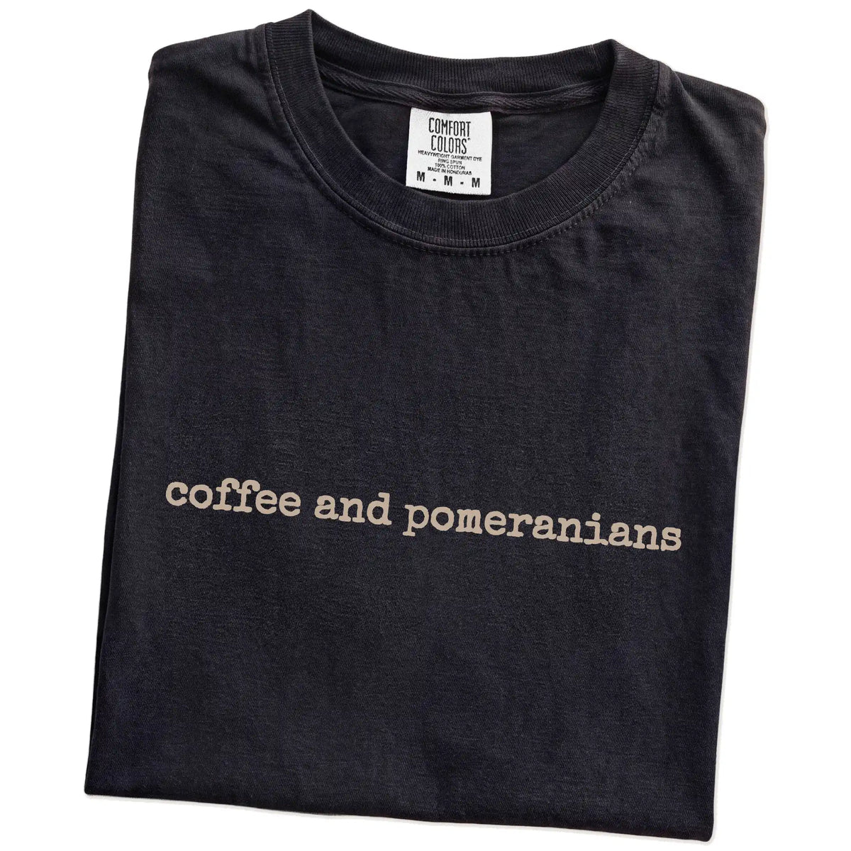 Folded Black Comfort Colors® T-shirt showing “coffee and pomeranians” retro text