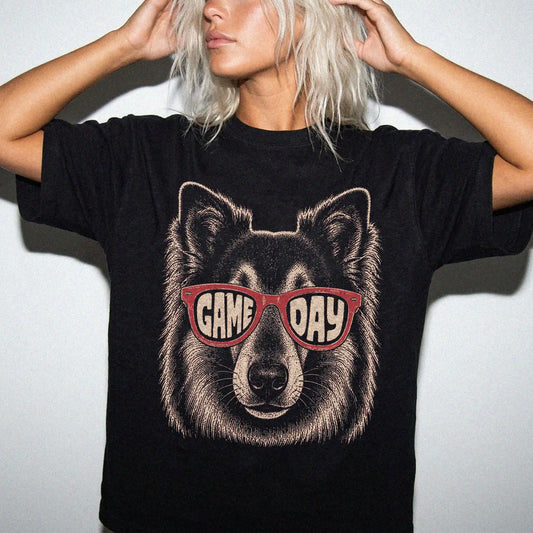 Model wearing a Black Comfort Colors® T-shirt with collie wearing red game day sunglasses