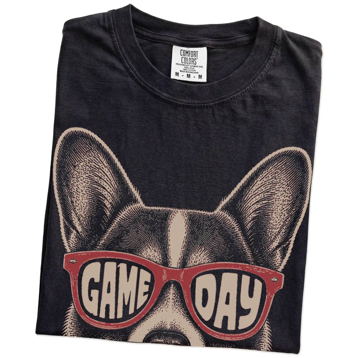 Folded Black Comfort Colors® T-shirt showing corgi wearing red game day sunglasses