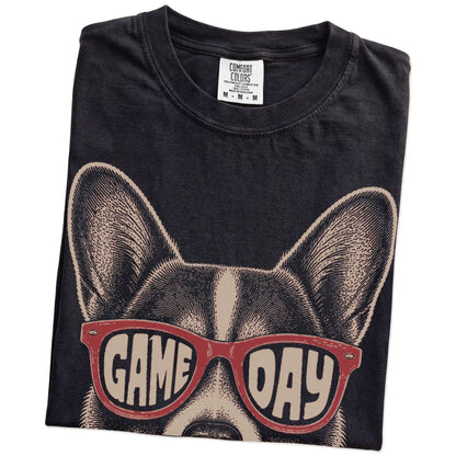 Folded Black Comfort Colors® T-shirt showing corgi wearing red game day sunglasses