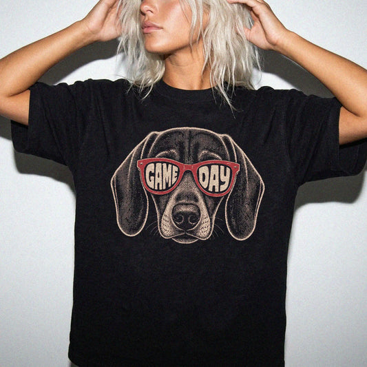 Model wearing a Black Comfort Colors® T-shirt with dachshund wearing red game day sunglasses