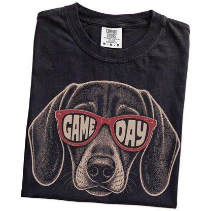 Folded Black Comfort Colors® T-shirt showing dachshund wearing red game day sunglasses