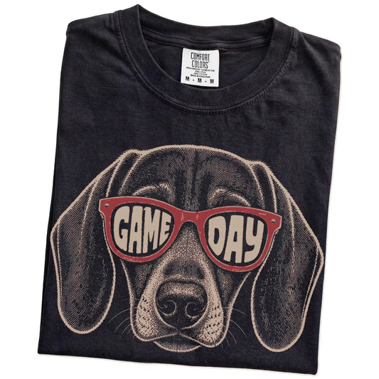 Folded Black Comfort Colors® T-shirt showing dachshund wearing red game day sunglasses