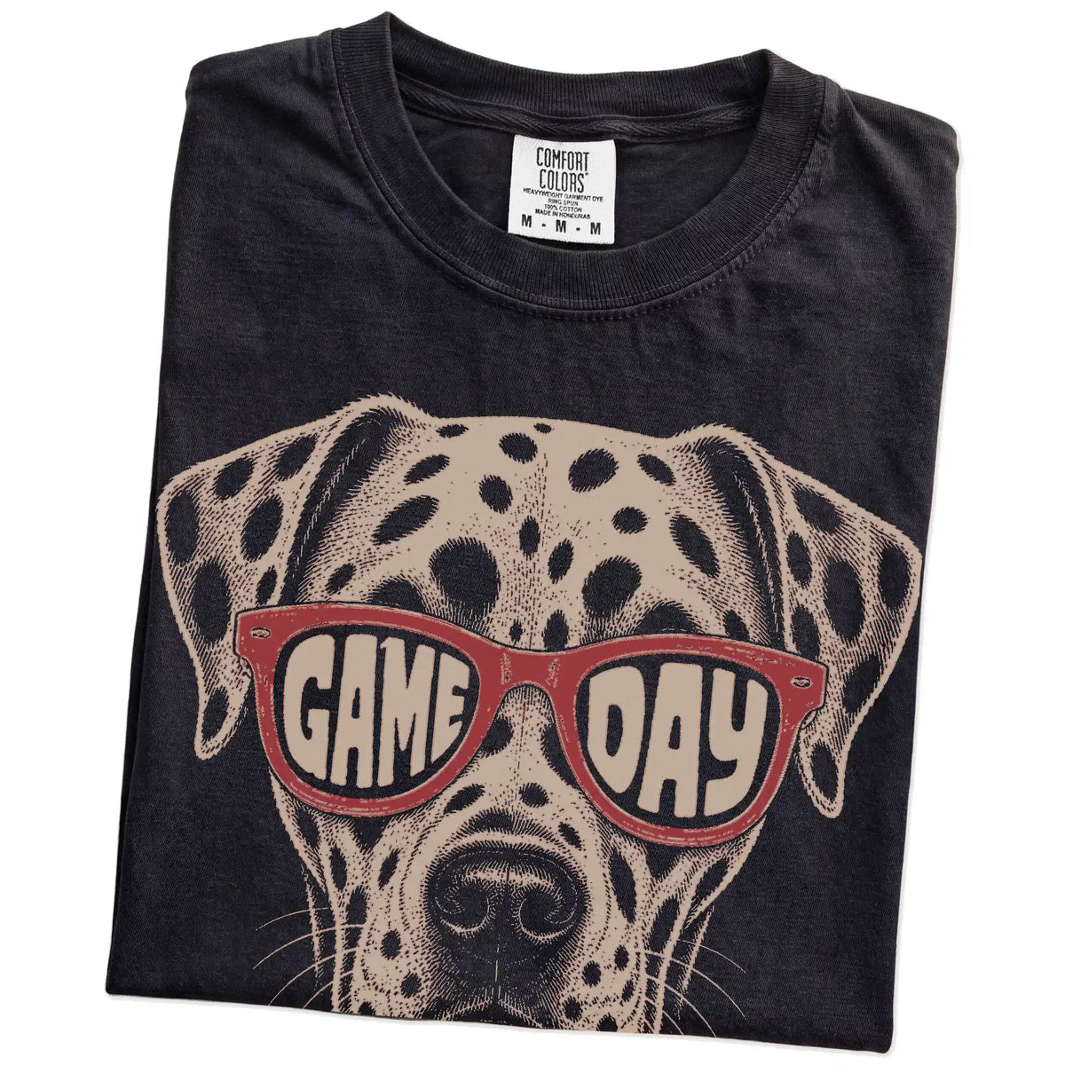 Folded Black Comfort Colors® T-shirt showing dalmatian wearing red game day sunglasses