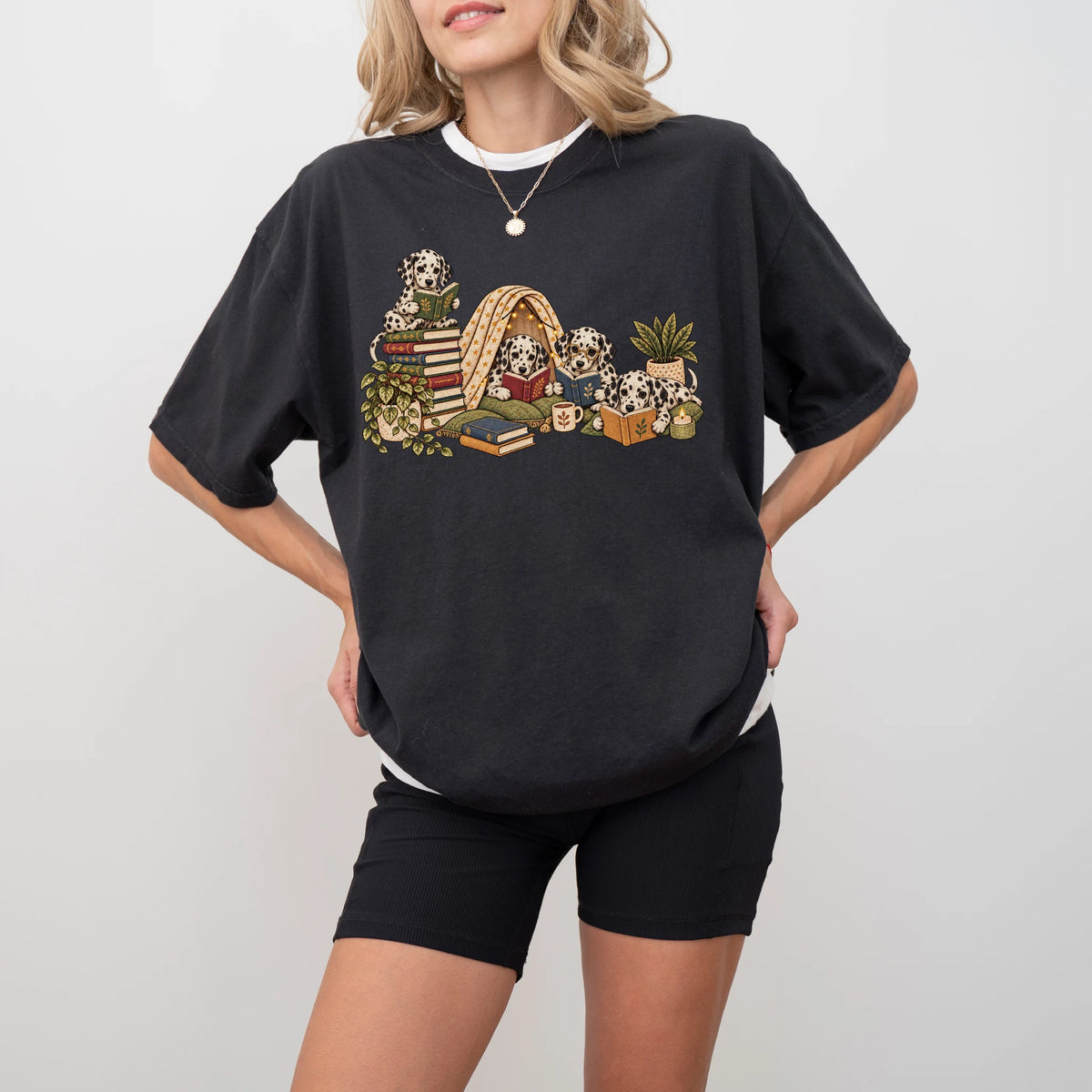 Dalmatian puppies reading books in a cozy blanket fort on a Black T-shirt worn by a model