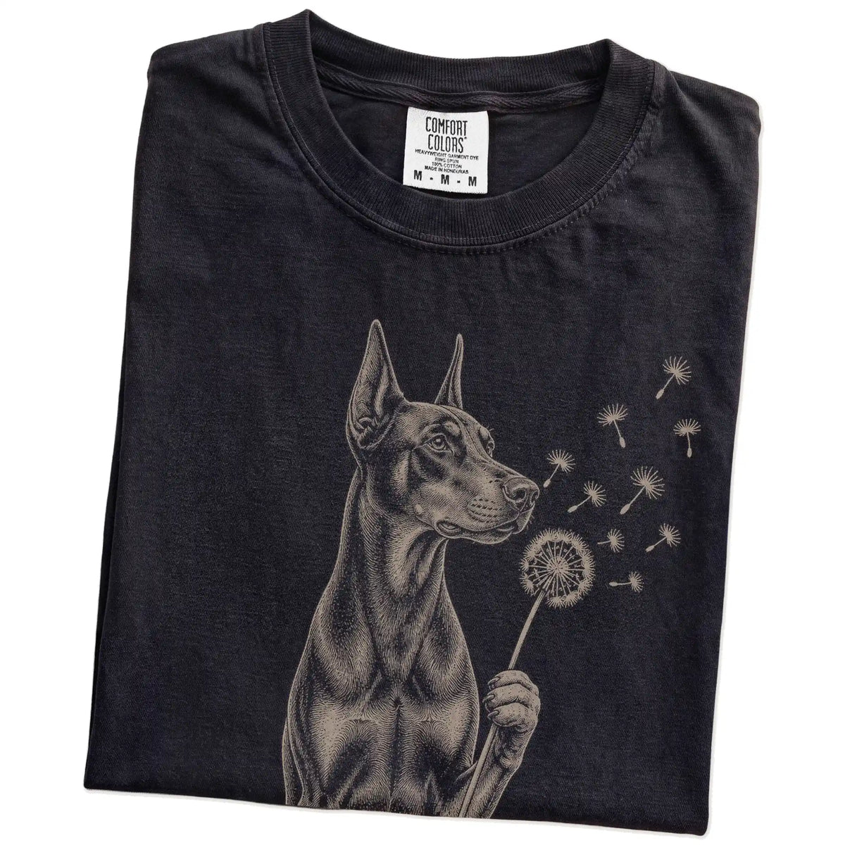 Folded Black Comfort Colors® T-shirt showing Doberman portrait with drifting dandelion seeds