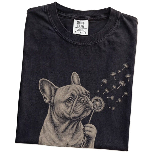 Folded Black Comfort Colors® T-shirt showing French Bulldog portrait with drifting dandelion seeds