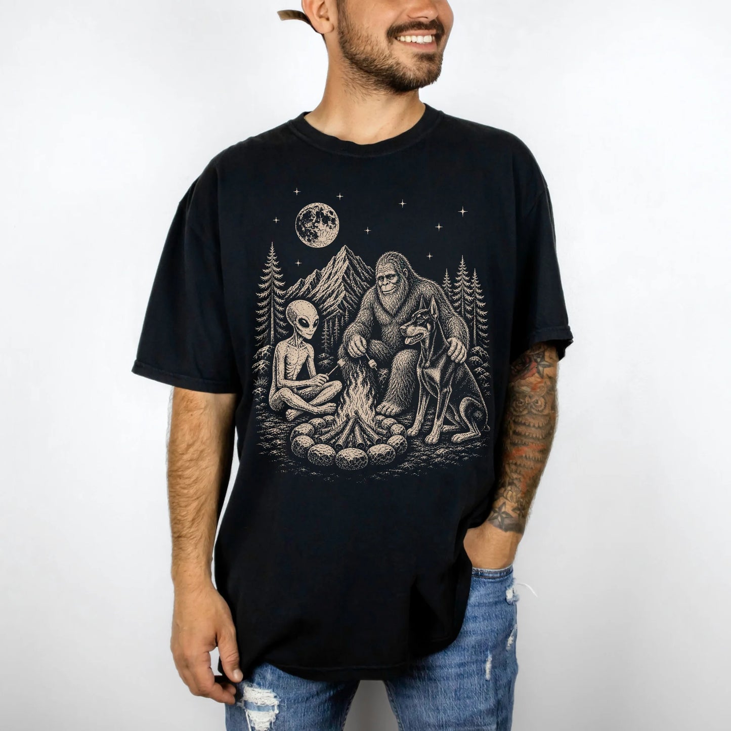 Model wearing a Black Comfort Colors® T-shirt showing Doberman camping with Bigfoot and an alien