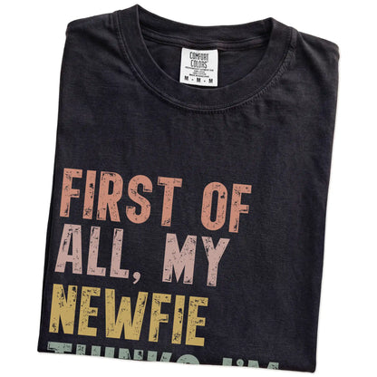 Folded Black Comfort Colors® T-shirt showing “My Newfie thinks I’m delightful” text