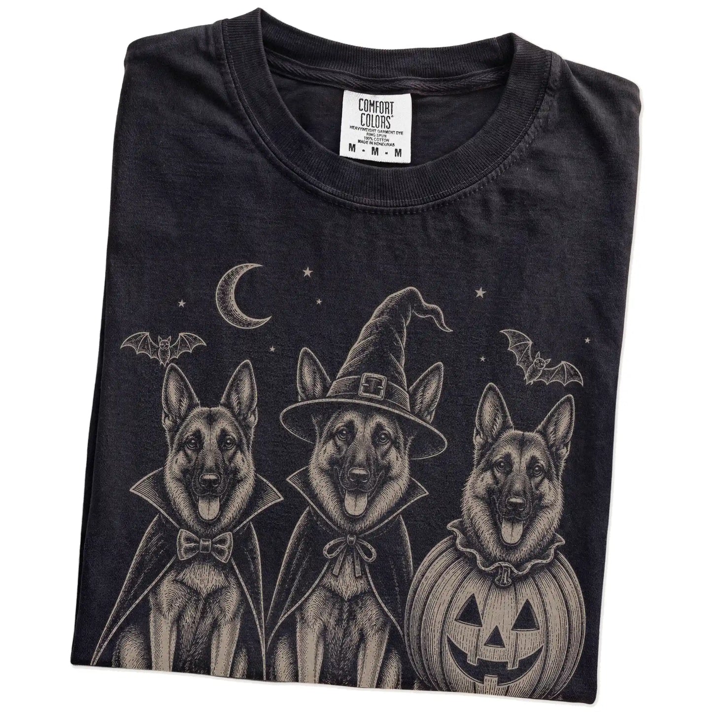 Folded Black Comfort Colors® T-shirt showing three German Shepherd dogs dressed for Halloween beneath bats and a crescent moo