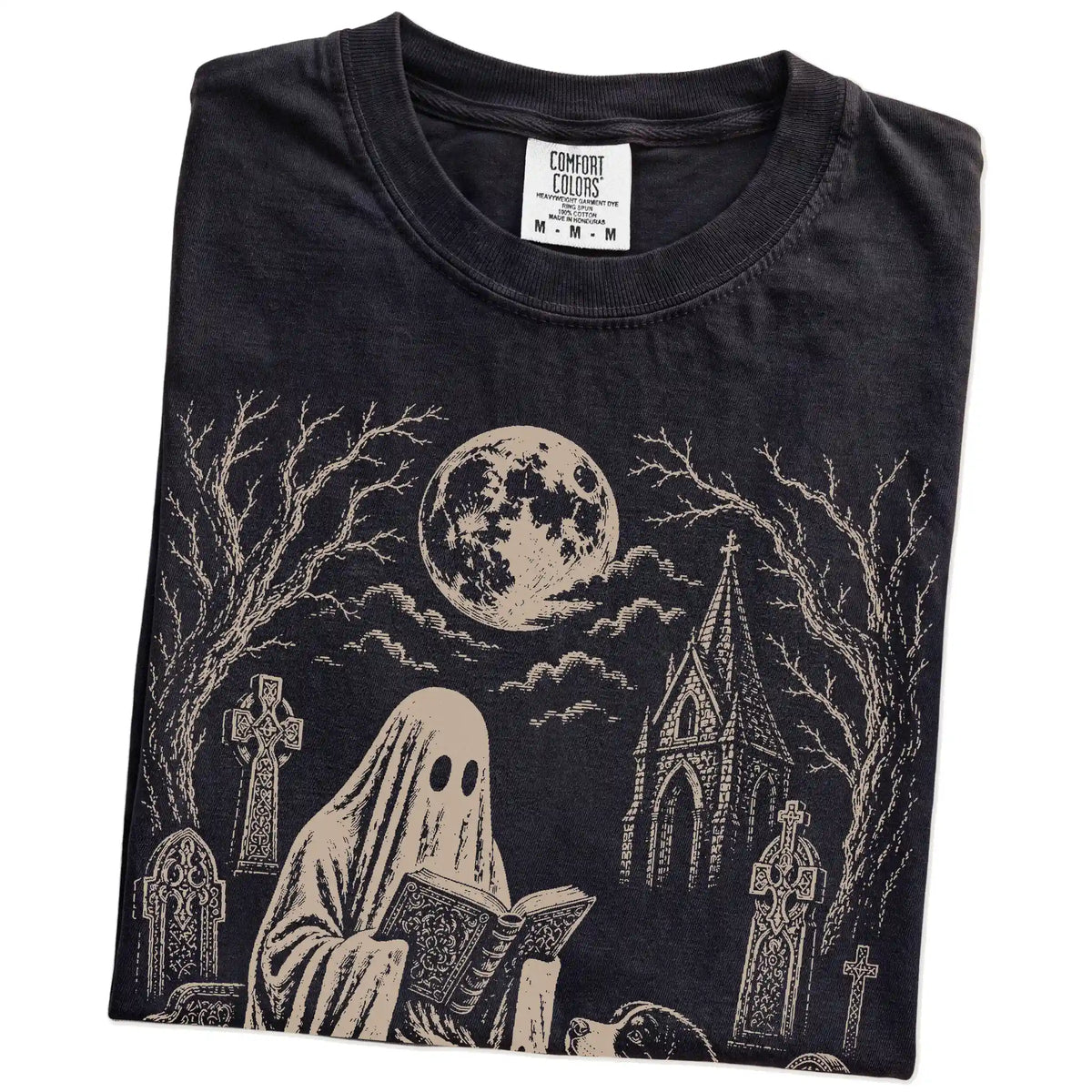 Folded Black Comfort Colors® T-shirt showing Bernese Mountain Dog beside a reading ghost in a moonlit graveyard