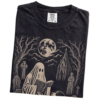 Folded Black Comfort Colors® T-shirt showing Bernese Mountain Dog beside a reading ghost in a moonlit graveyard