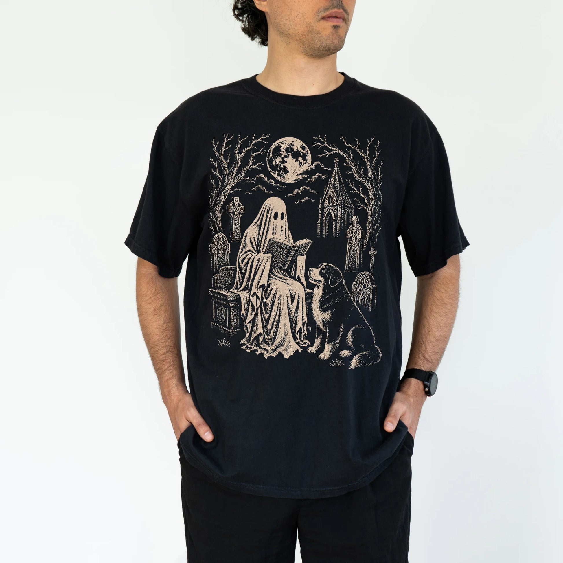 Model wearing a Black Comfort Colors® T-shirt showing Bernese Mountain Dog beside a reading ghost in a moonlit graveyard