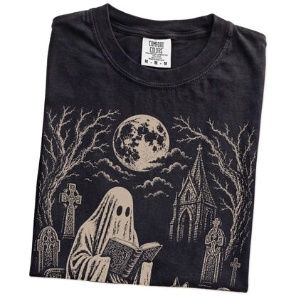 Folded Black Comfort Colors® T-shirt showing Husky beside a reading ghost in a moonlit graveyard
