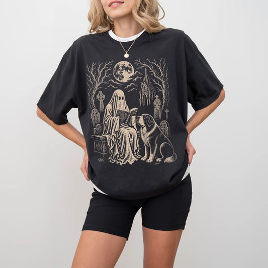 Model wearing a Black Comfort Colors® T-shirt showing Saint Bernard beside a reading ghost in a moonlit graveyard