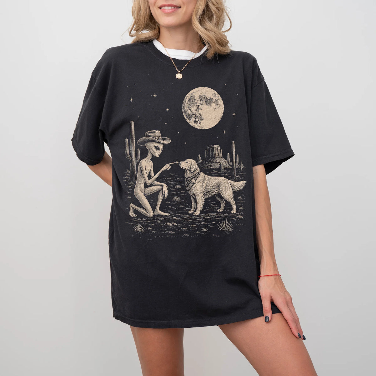Model wearing a Black Comfort Colors® T-shirt with cowboy alien fist-bumping a golden retriever beneath the moon