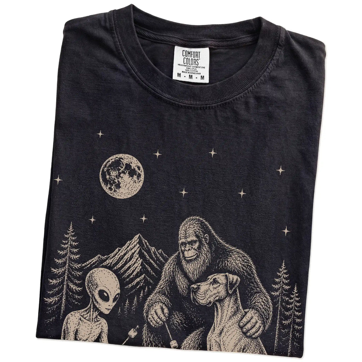 Folded Black Comfort Colors® T-shirt showing Great Dane camping with Bigfoot and an alien