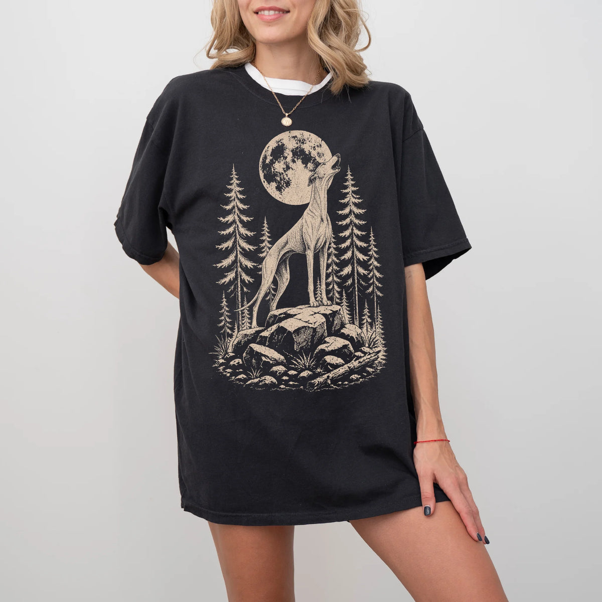Model wearing a Black Comfort Colors® T-shirt with a Greyhound howling beneath the moon and pine trees