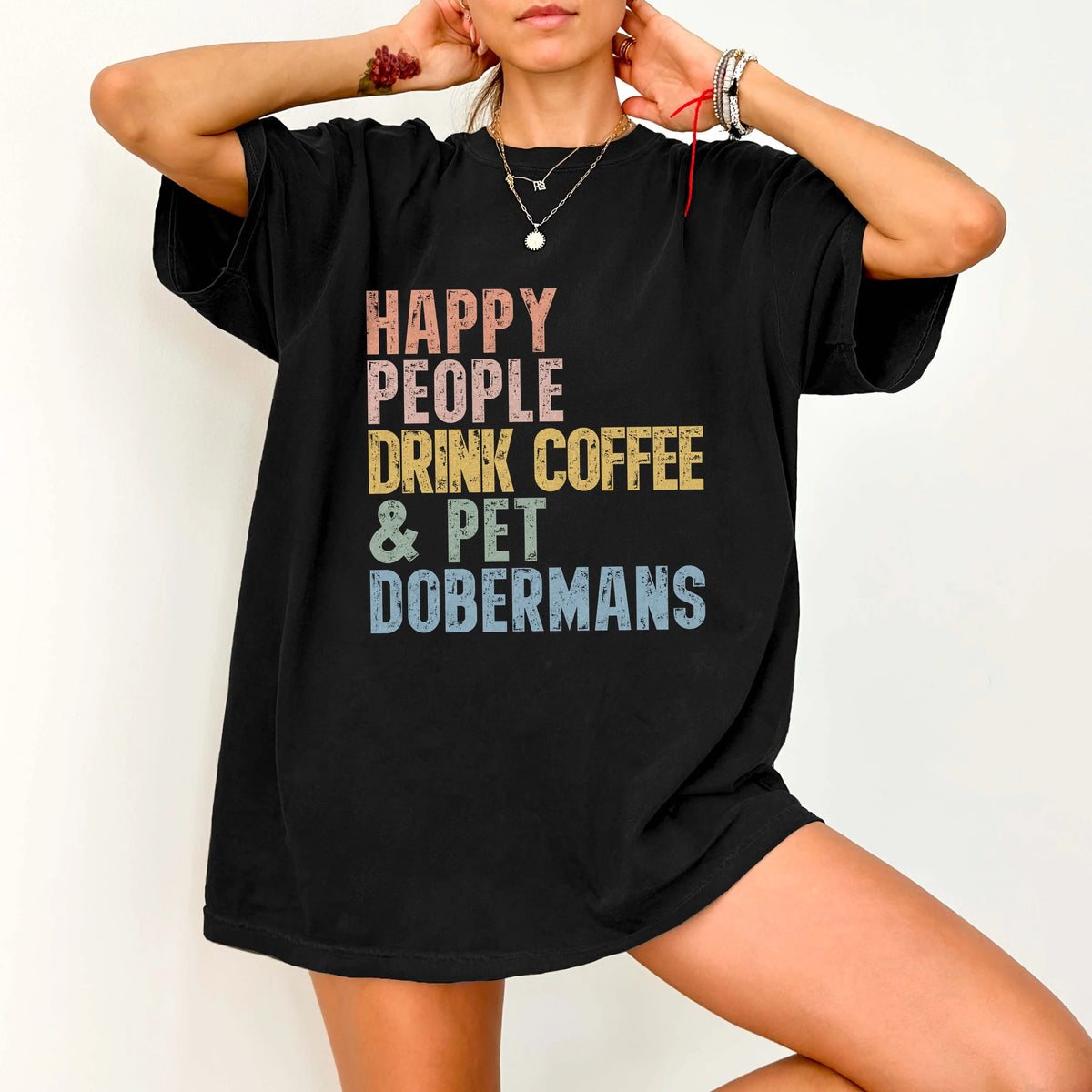 Model wearing a Black Comfort Colors® T-shirt featuring Doberman with coffee and “Happy People Drink Coffee and Pet Dogs” let