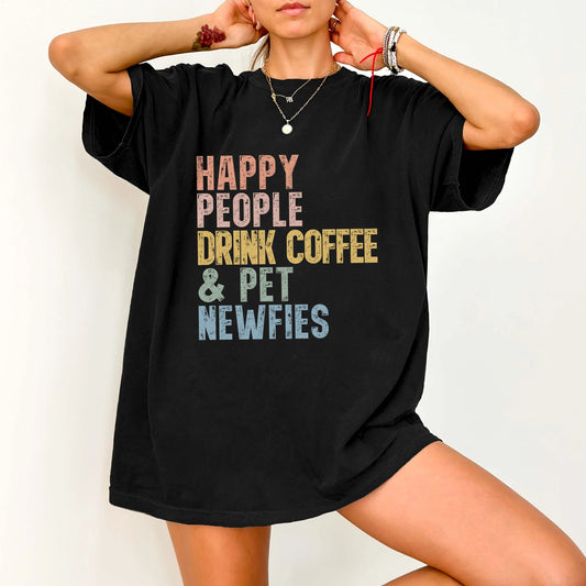 Model wearing a Black Comfort Colors® T-shirt featuring Newfie with coffee and “Happy People Drink Coffee and Pet Dogs” lette