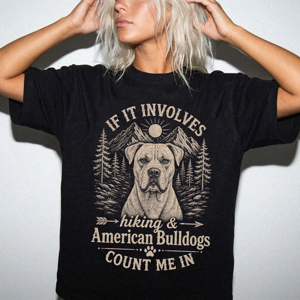 Model wearing a Black Comfort Colors® T-shirt featuring American Bulldog hiking design with mountain scenery