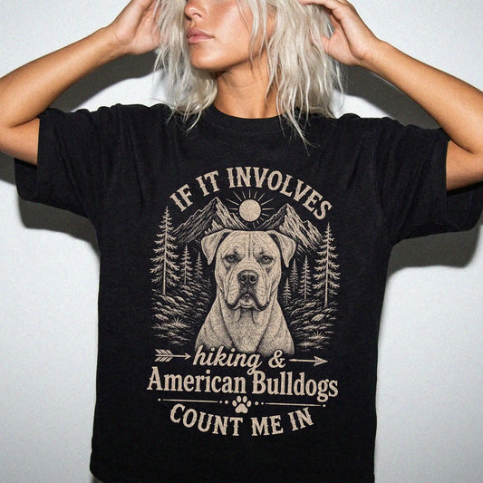 Model wearing a Black Comfort Colors® T-shirt featuring American Bulldog hiking design with mountain scenery