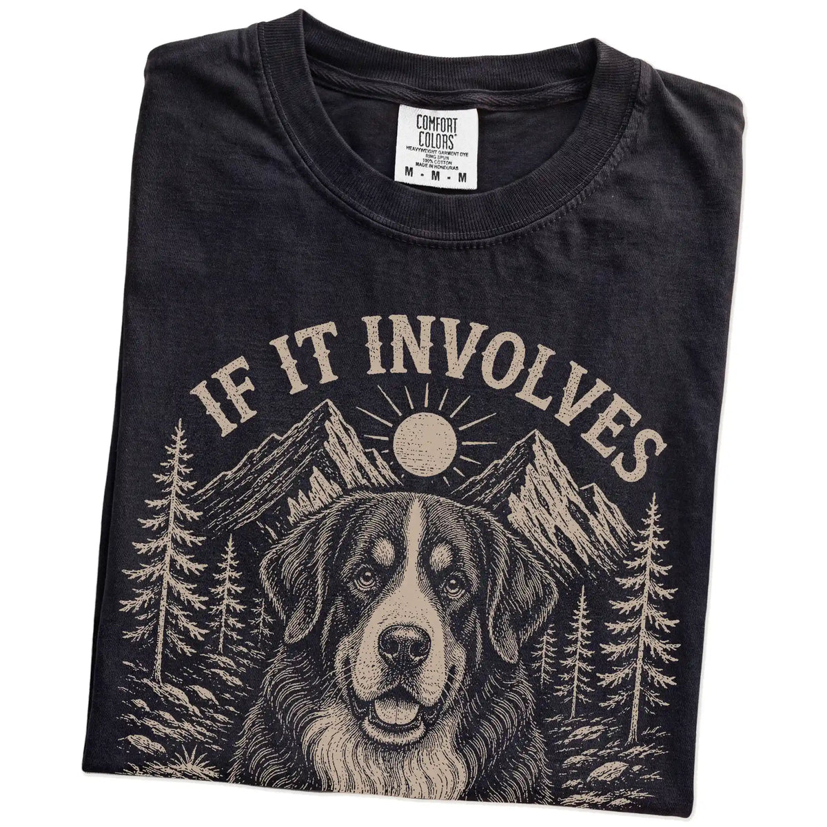 Folded Black Comfort Colors® T-shirt showing Bernese Mountain Dog hiking design with mountain scenery
