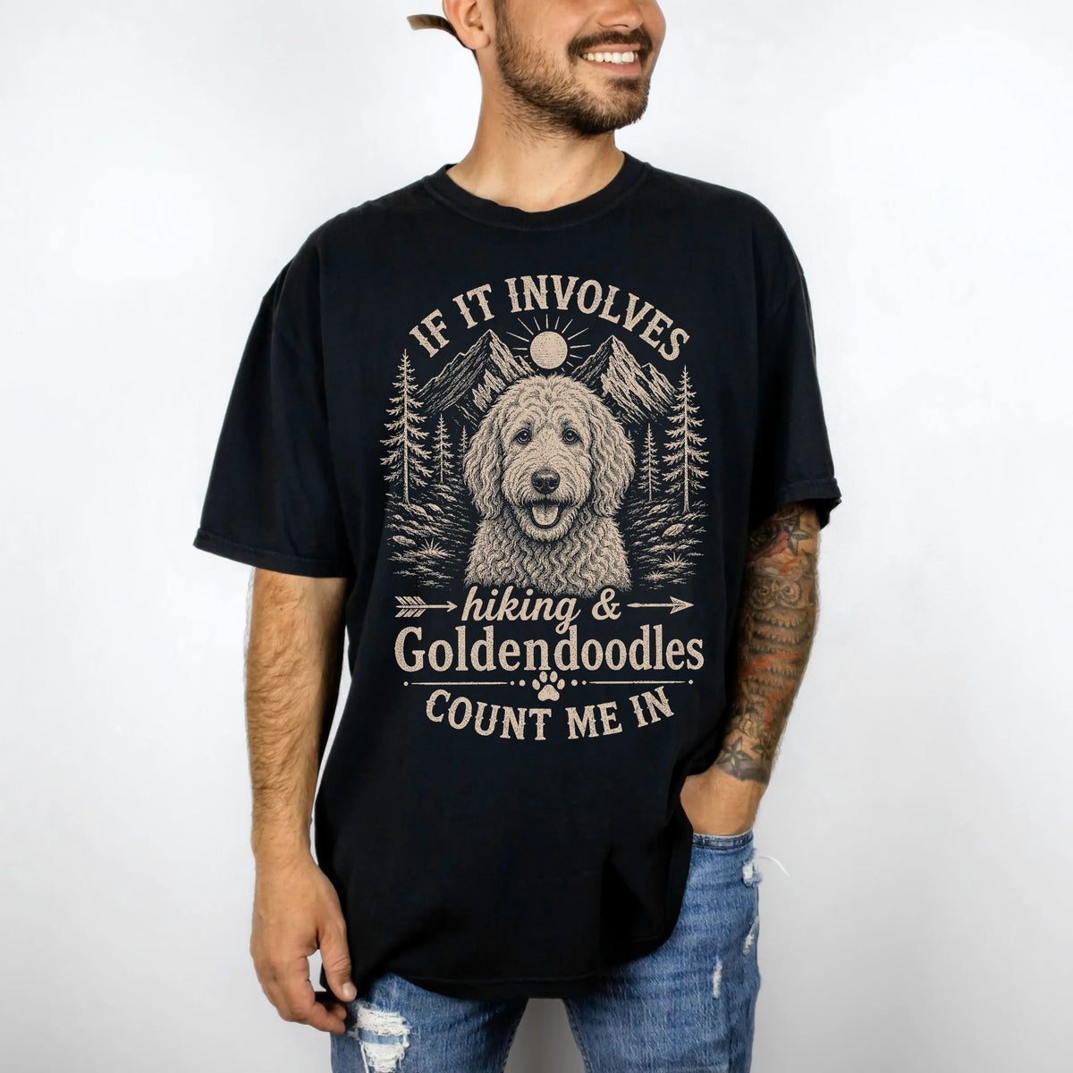 Model wearing a Black Comfort Colors® T-shirt featuring Goldendoodle hiking design with mountain scenery