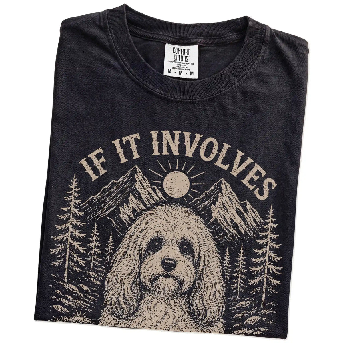 Folded Black Comfort Colors® T-shirt showing Havanese hiking design with mountain scenery