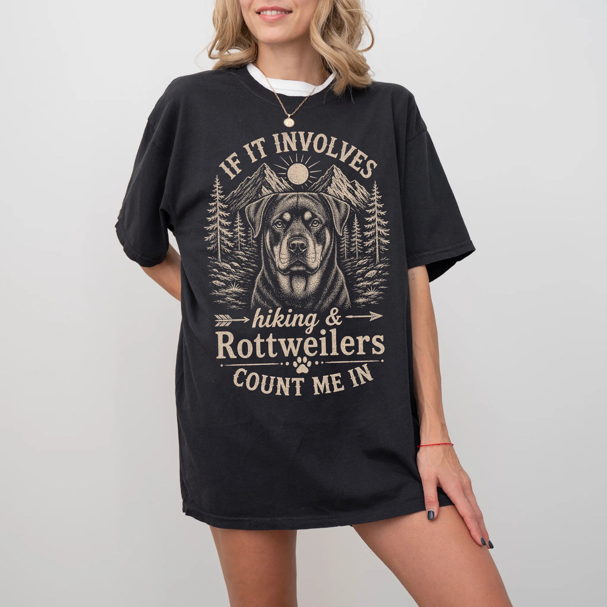 Model wearing a Black Comfort Colors® T-shirt featuring Rottweiler hiking design with mountain scenery