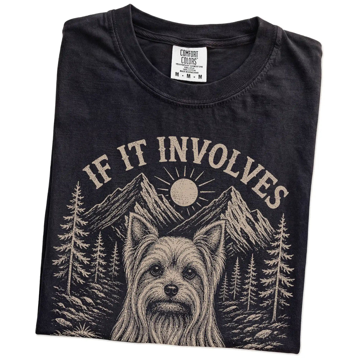 Folded Black Comfort Colors® T-shirt showing Yorkie hiking design with mountain scenery