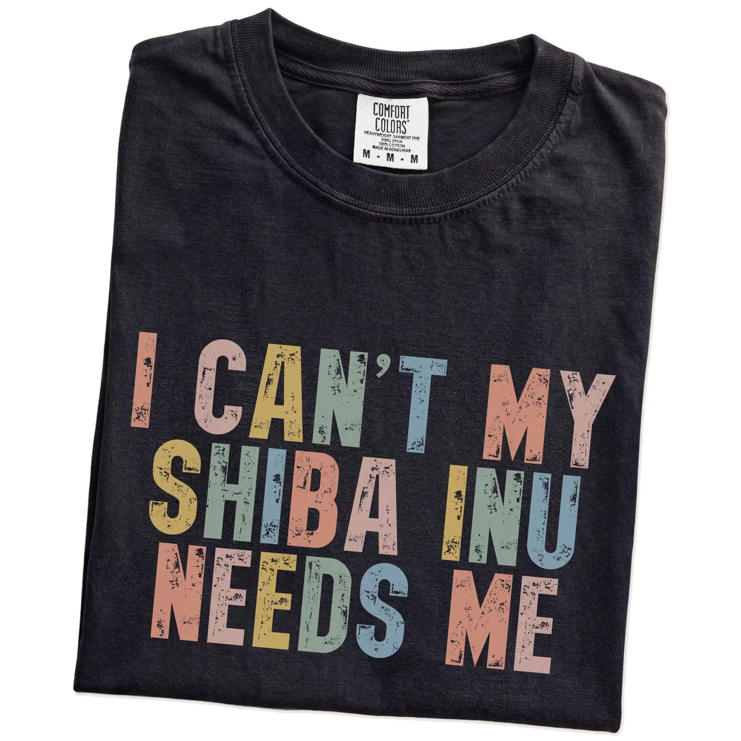 Folded Black Comfort Colors® T-shirt showing Shiba Inu with “I Can’t, My Dog Needs Me” lettering