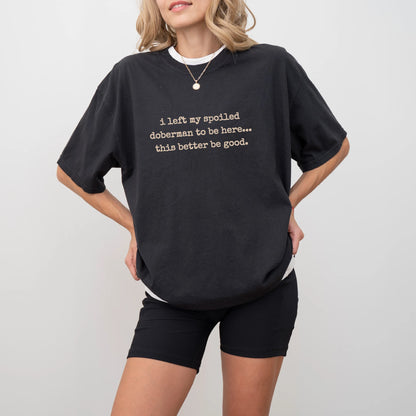 Model wearing a Black Comfort Colors® T-shirt featuring the “I Left My Spoiled Doberman Home” saying
