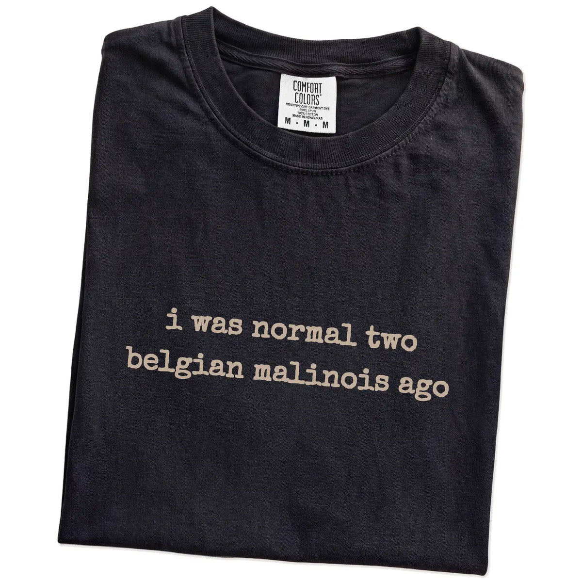 Folded Black Comfort Colors® T-shirt showing i was normal two belgian malinois ago lettering