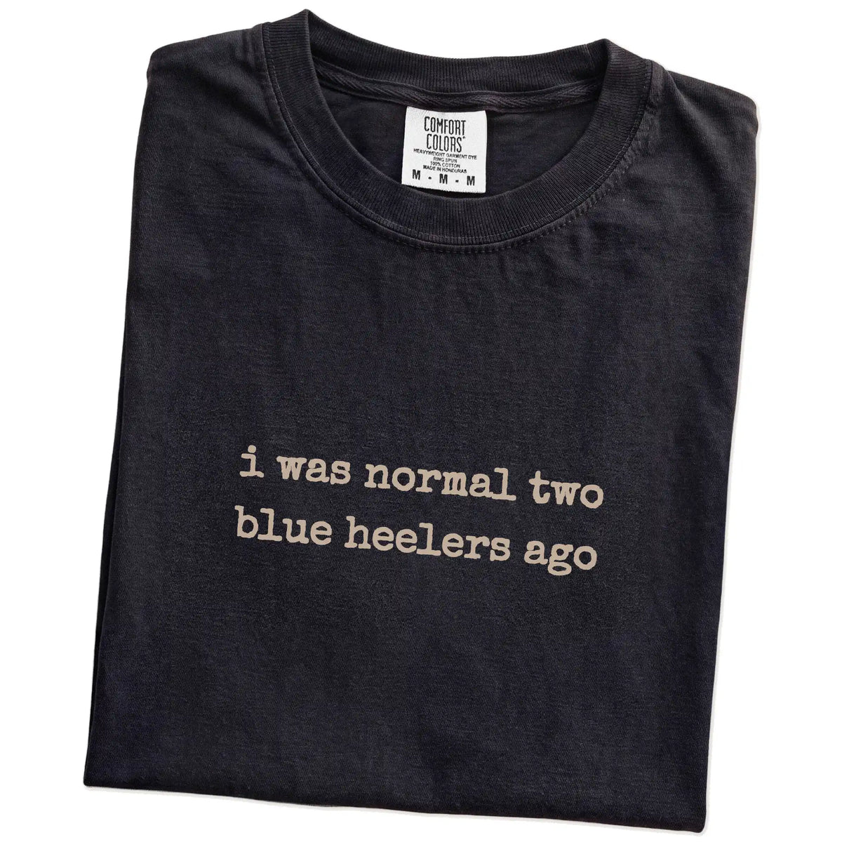 Folded Black Comfort Colors® T-shirt showing i was normal two blue heelers ago lettering