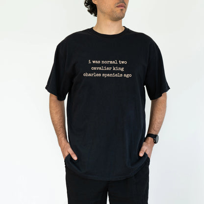 Model wearing a Black Comfort Colors® T-shirt with i was normal two cavalier king charles spaniels ago lettering
