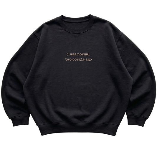 Black I Was Normal Two Corgis Ago sweatshirt laid flat