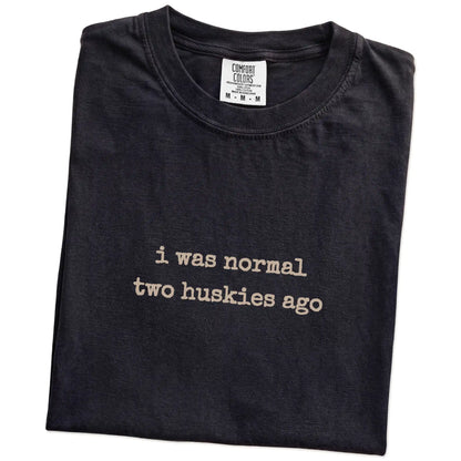 Folded Black Comfort Colors® T-shirt showing i was normal two huskies ago lettering