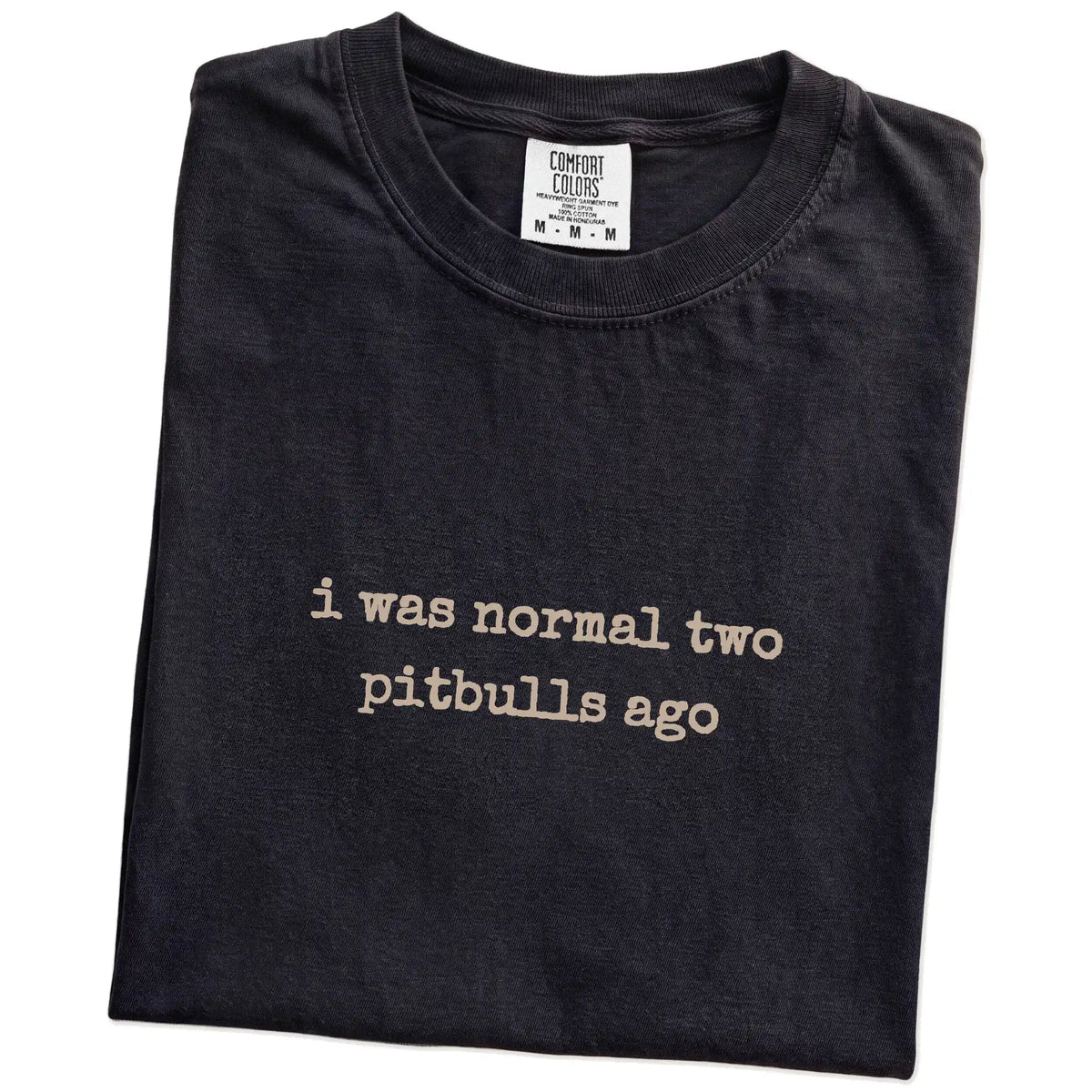 Folded Black Comfort Colors® T-shirt showing i was normal two pitbulls ago lettering