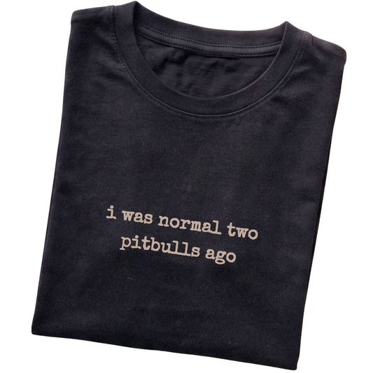 Black I Was Normal Two Pitbulls Ago T-shirt folded to show the printed design