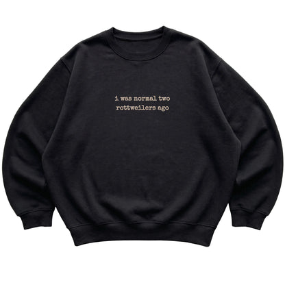 Black I Was Normal Two Rottweilers Ago sweatshirt laid flat