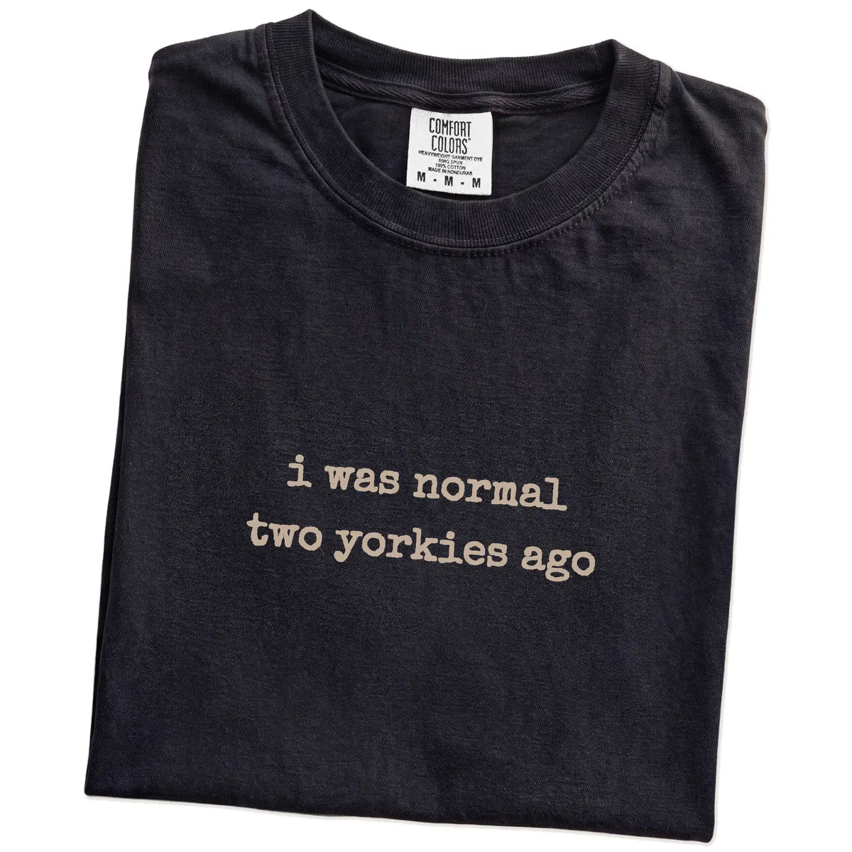 Folded Black Comfort Colors® T-shirt showing i was normal two yorkies ago lettering